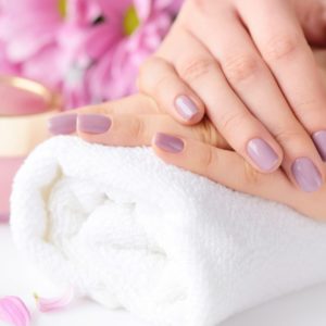 Women's hands with pink manicure are on a towel