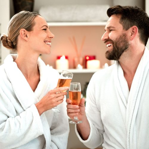 Champagne, toast and couple in celebration at a spa for love, marriage or birthday together. Happy, relax and calm man and woman cheers with glass of alcohol to celebrate anniversary at a hotel.