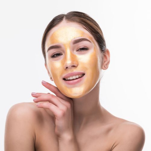 Beautiful woman with Golden mask on face skin cosmetic touch Face. Beauty Skincare and Treatment